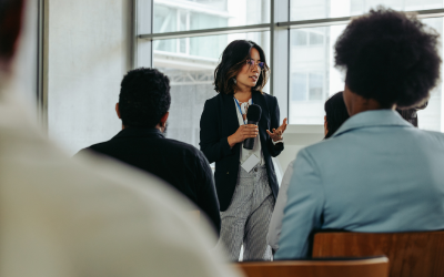 Person talking on a microphone in a room full of people