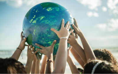 Children at the beach holding up a planet in their hands