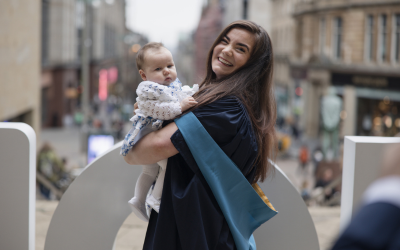 OU alumna Zara Mahon at her degree ceremony, with her child.