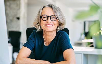 A woman sitting at a desk, smiling direct at the camera