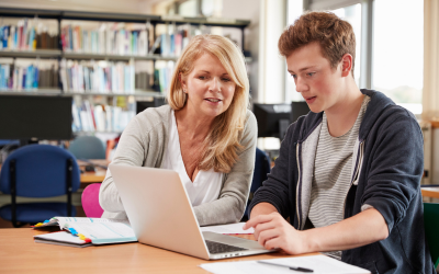 A teacher supporting a student in the library